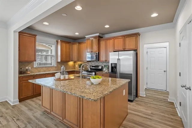 a kitchen with stainless steel appliances granite countertop a stove top oven a sink and a refrigerator