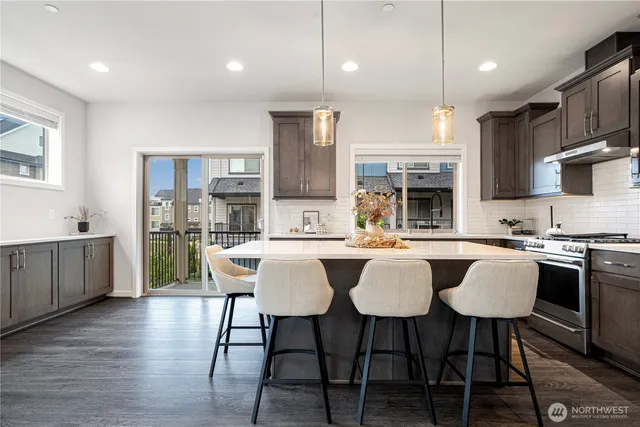 a kitchen with stainless steel appliances granite countertop a kitchen island a table and chairs in it