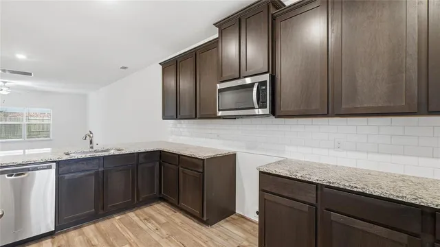 a kitchen with stainless steel appliances granite countertop a sink stove and microwave