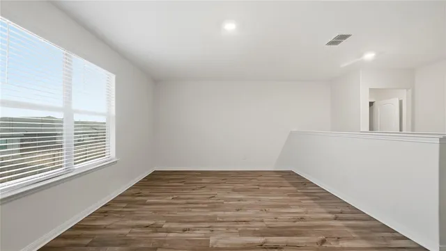 a view of empty room with wooden floor and fan