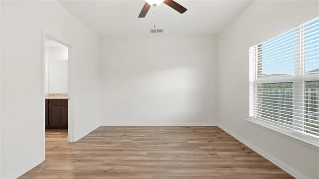 a view of an empty room with window and wooden floor