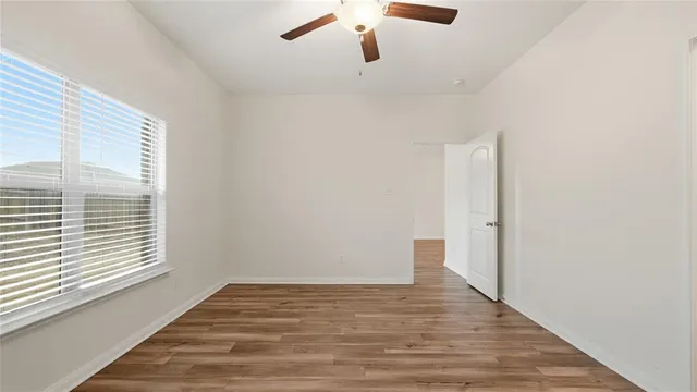 a view of an empty room with wooden floor and a window