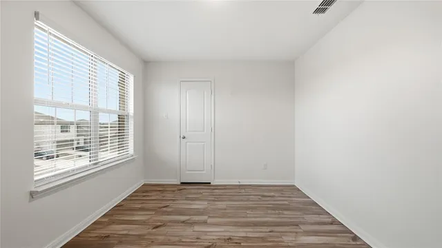 a view of an empty room with wooden floor and a window