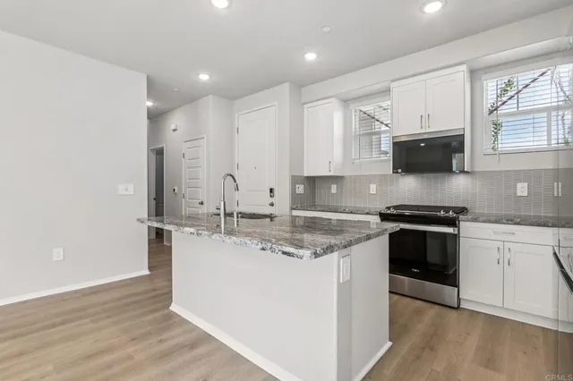 a kitchen with stainless steel appliances granite countertop a stove a sink and a microwave