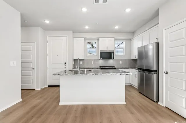 a kitchen with kitchen island a sink a stove a refrigerator and white cabinets