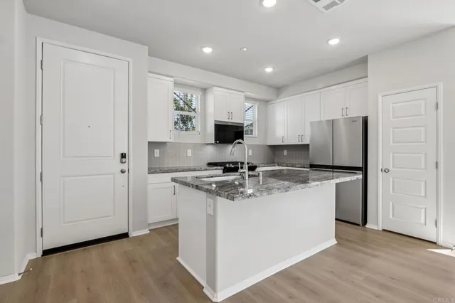 a kitchen with stainless steel appliances granite countertop a stove top oven a sink and a refrigerator