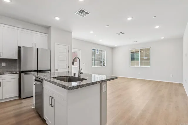 a kitchen with kitchen island granite countertop a sink and refrigerator