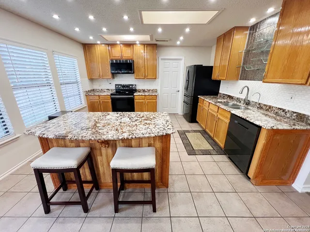 a kitchen with stainless steel appliances granite countertop table chairs sink and cabinets