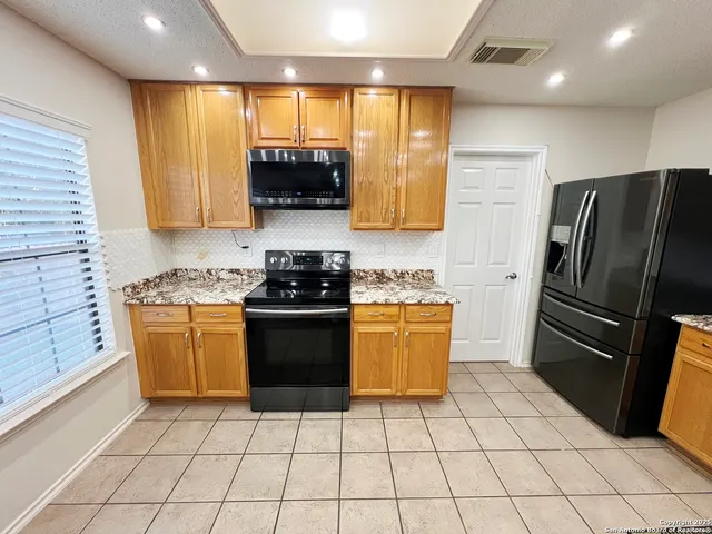 a kitchen with stainless steel appliances granite countertop a refrigerator a stove a sink and a microwave