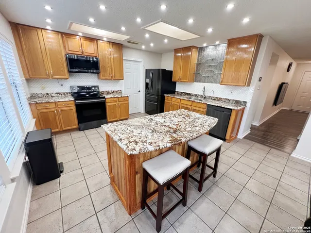 a kitchen with stainless steel appliances kitchen island granite countertop a refrigerator and a stove top oven