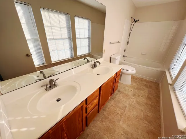 a bathroom with a double vanity sink a large mirror and a bathtub