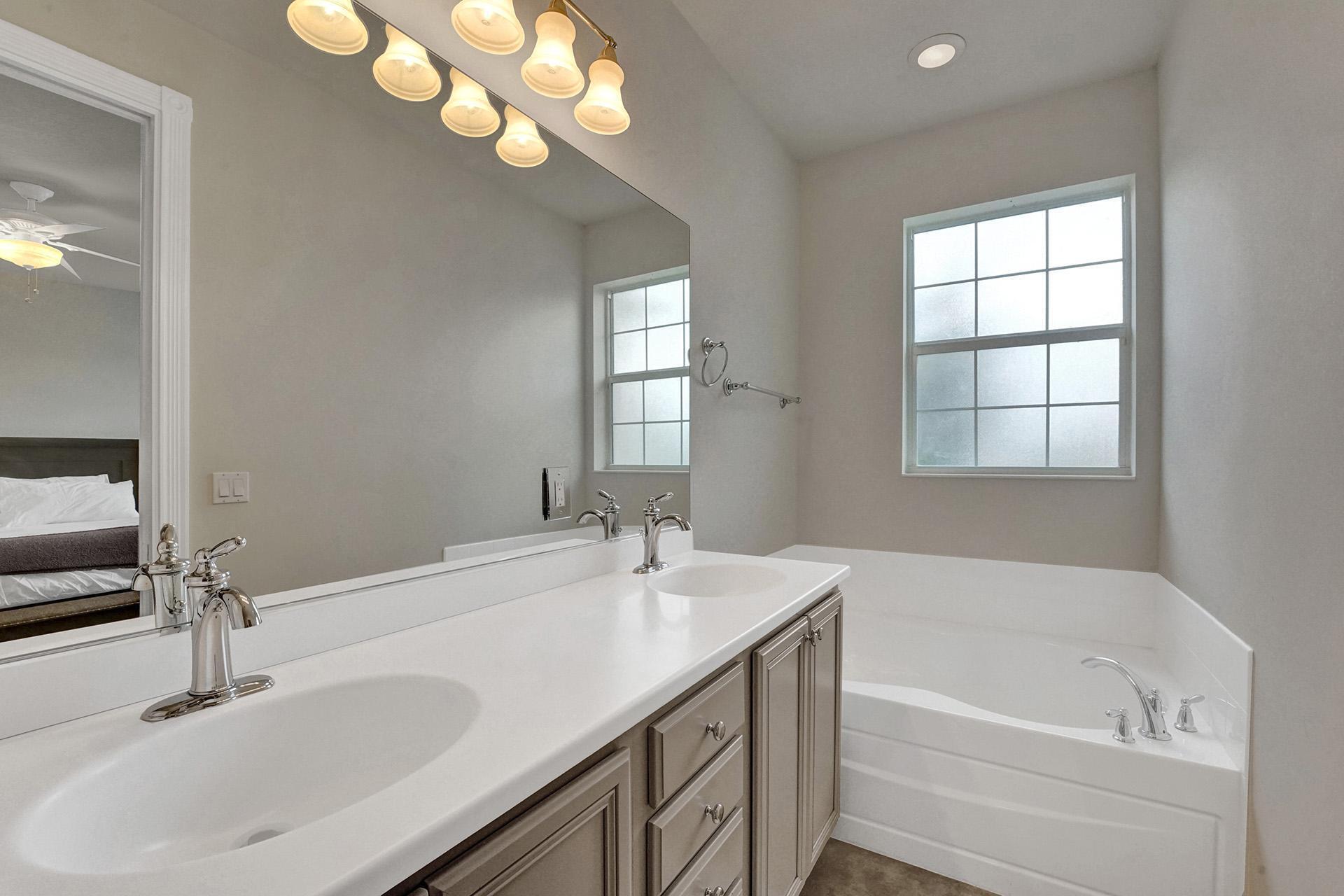 1172 Islamorada Drive Jupiter, FL 33458 - Photo 31 of 42 a bathroom with a tub a double vanity sink and a mirror