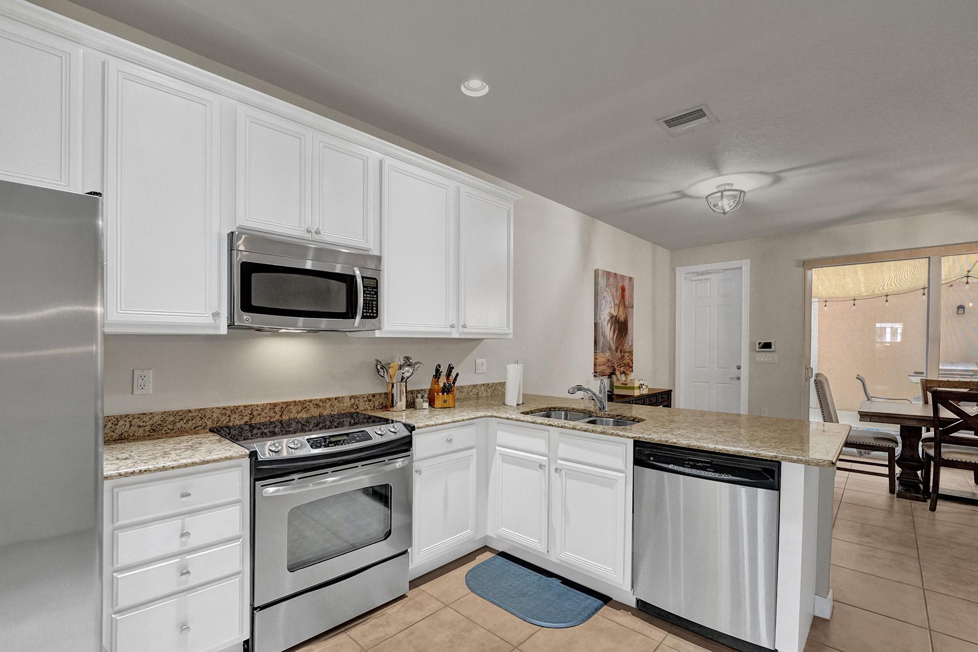1172 Islamorada Drive Jupiter, FL 33458 - Photo 9 of 42 a kitchen with granite countertop white cabinets and white appliances