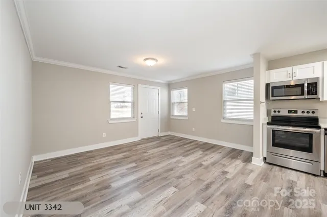 a view of an empty room with a window and a kitchen
