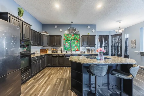 a very nice looking kitchen with granite countertop a large counter top space a sink stainless steel appliances and cabinets