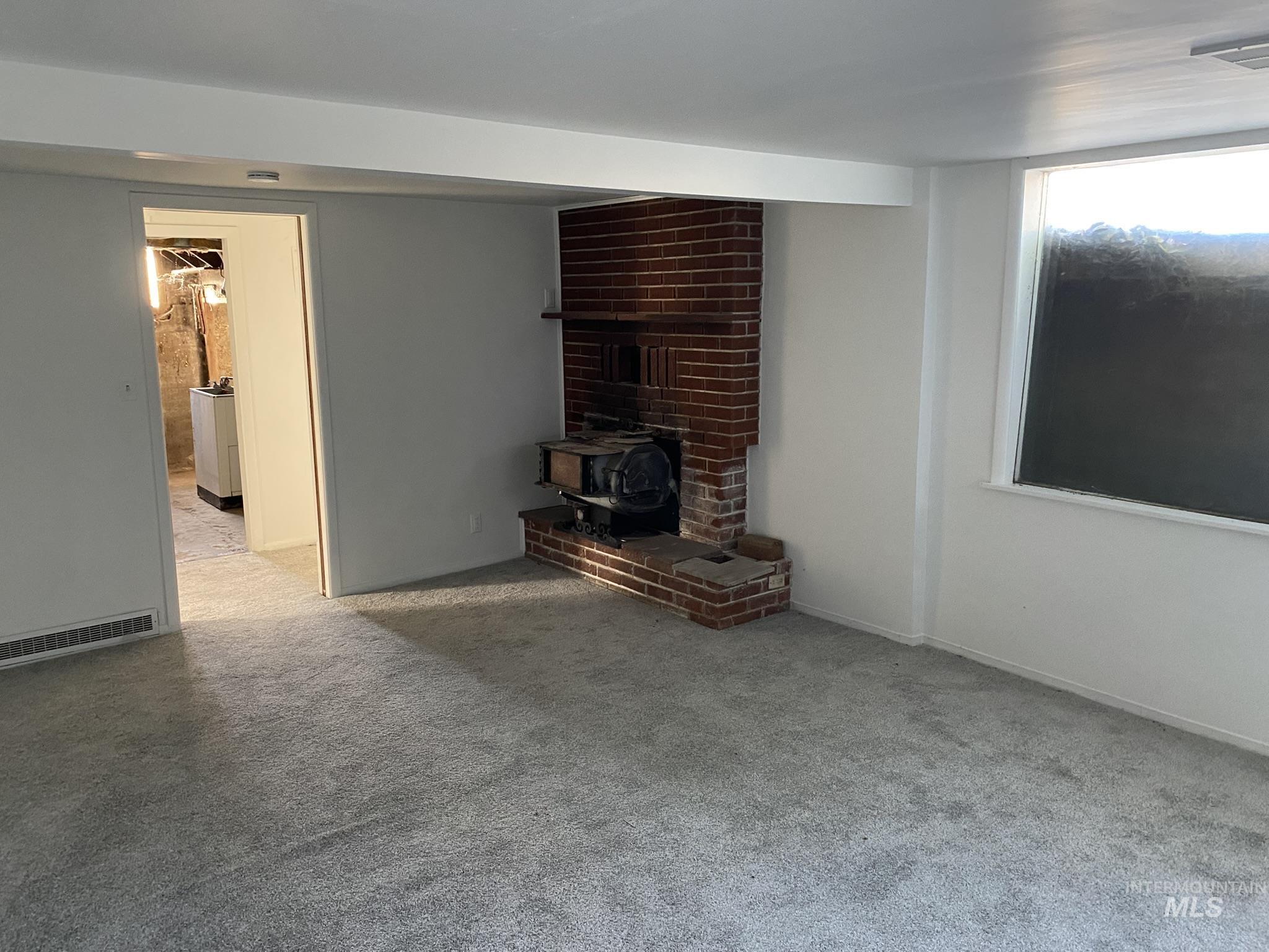 1967 North Fry Street Boise, ID 83704 - Photo 10 of 15 Unfurnished living room featuring a wood stove and light carpet