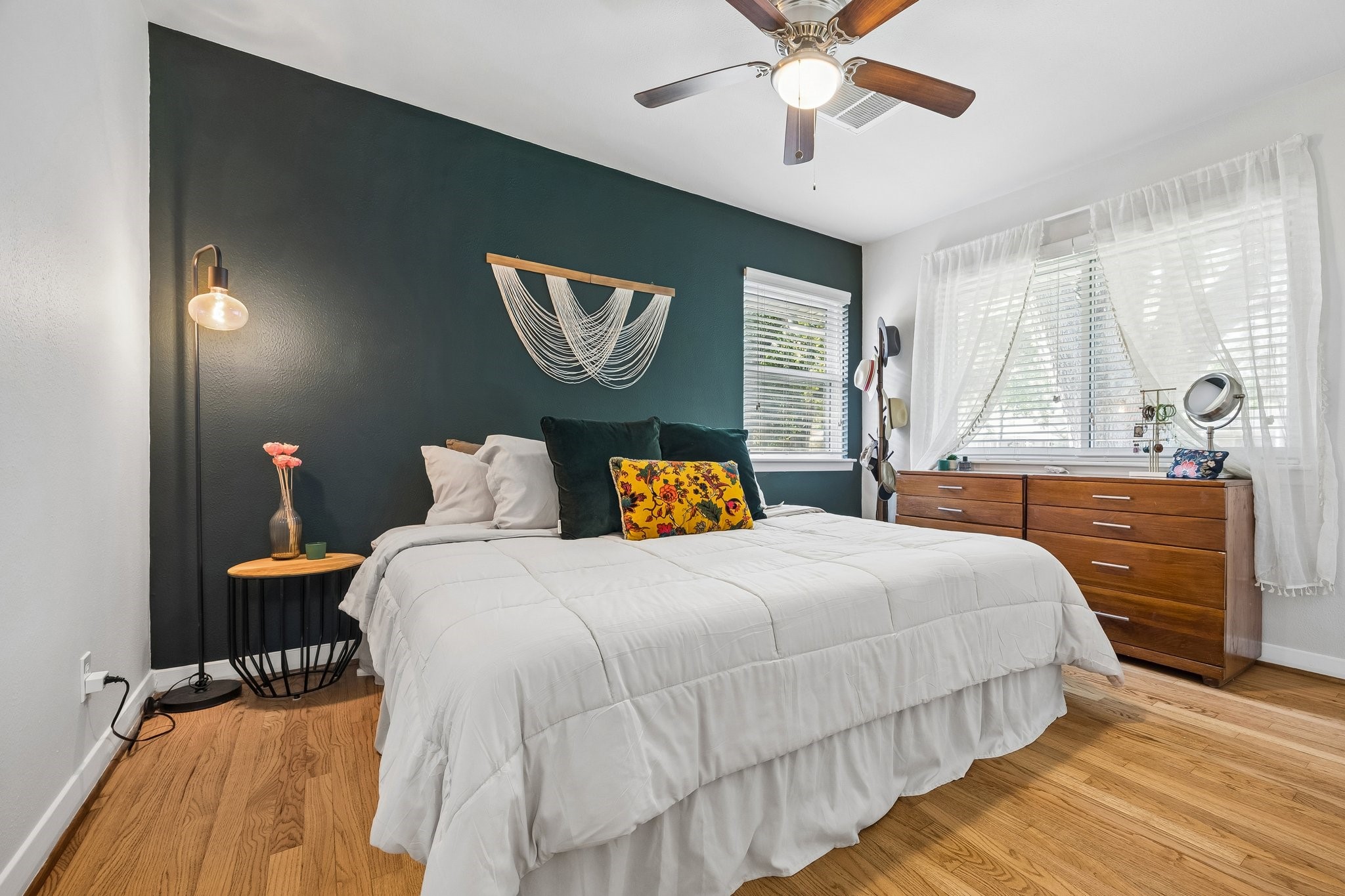 4514 Warm Springs Road Houston, TX 77035 - Photo 21 of 31 The comfortable primary bedroom features hardwood floors, a dark green accent wall, and a ceiling fan. It includes large windows inviting in natural light. A MCM sliding mirror door closet is to the left.(not pictured)