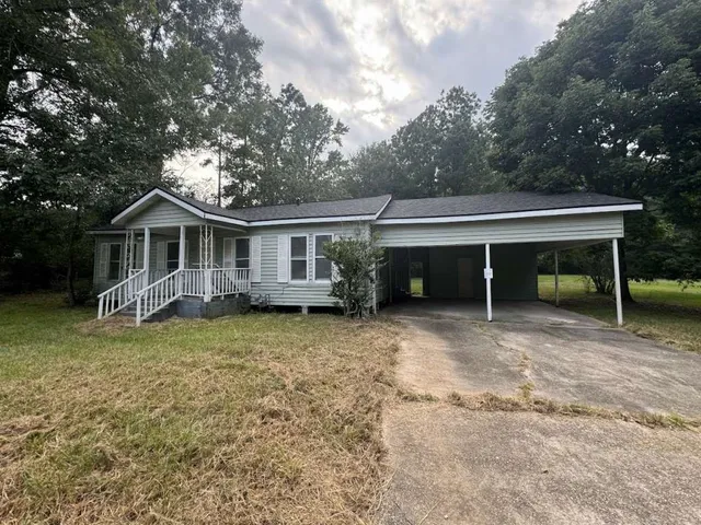 a view of a house with a yard and a large tree