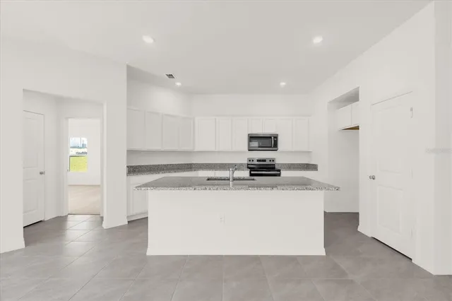 a kitchen with stainless steel appliances a sink a stove a refrigerator a sink a counter top space and cabinets