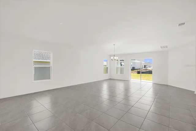 a view of empty room with kitchen view and wooden floor