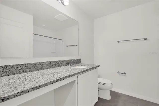 a bathroom with a granite countertop sink a toilet and a mirror