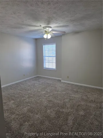 en empty room with windows and chandelier fan