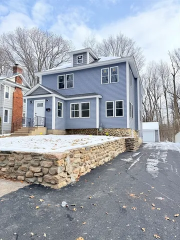 a front view of a house with a yard covered with snow