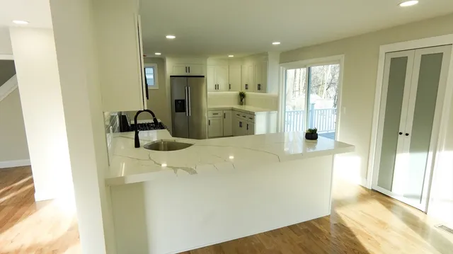 a large white kitchen with a sink a refrigerator and a window