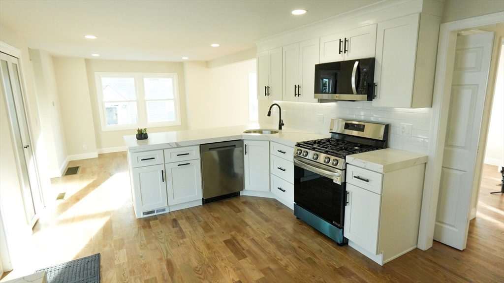 122 Copperfield Road Worcester, MA 01602 - Photo 7 of 28 a kitchen with stainless steel appliances a white stove top oven a sink dishwasher and a microwave oven with cabinets
