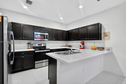 a kitchen with stainless steel appliances a sink a stove a refrigerator a washer dryer and a refrigerator