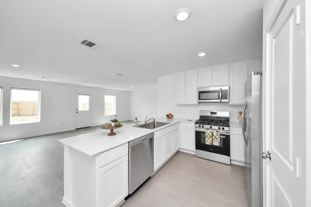 a kitchen with stainless steel appliances granite countertop a sink stove and refrigerator