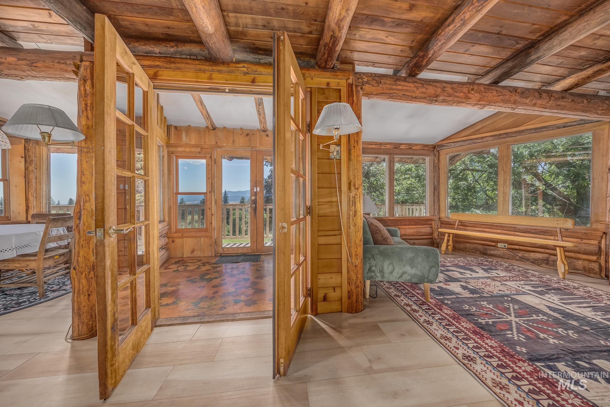 2150 Seid Creek Road Cambridge, ID 83610 - Photo 12 of 50 Double French doors opening to an additional room featuring exposed wood beams, wood paneling, and multiple windows