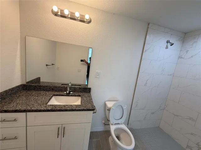 a bathroom with a granite countertop toilet sink and mirror
