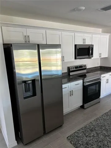 a kitchen with stainless steel appliances granite countertop a refrigerator a stove a sink and a microwave