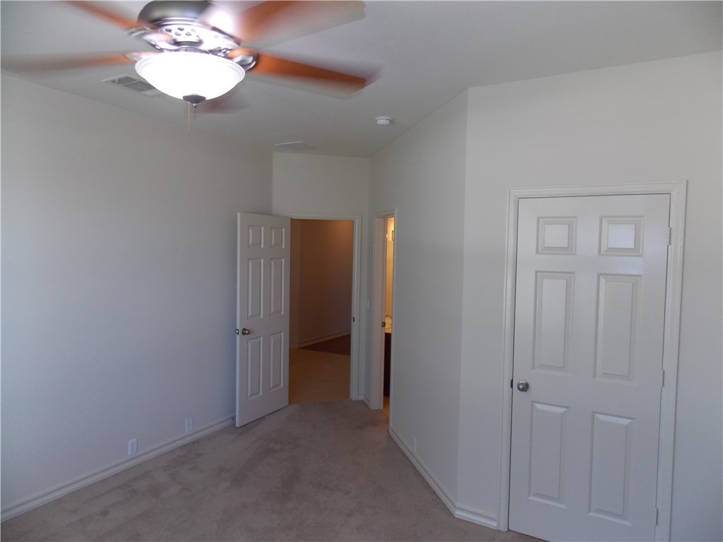20961 Mandrake Drive Pflugerville, TX 78660 - Photo 11 of 34 an empty room with a chandelier fan and a bathroom