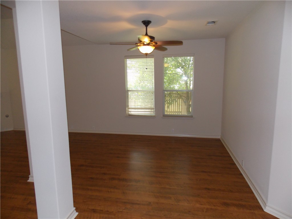 20961 Mandrake Drive Pflugerville, TX 78660 - Photo 14 of 34 an empty room with wooden floor chandelier fan and windows