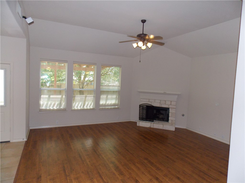 20961 Mandrake Drive Pflugerville, TX 78660 - Photo 15 of 34 a view of an empty room with wooden floor fireplace and a window
