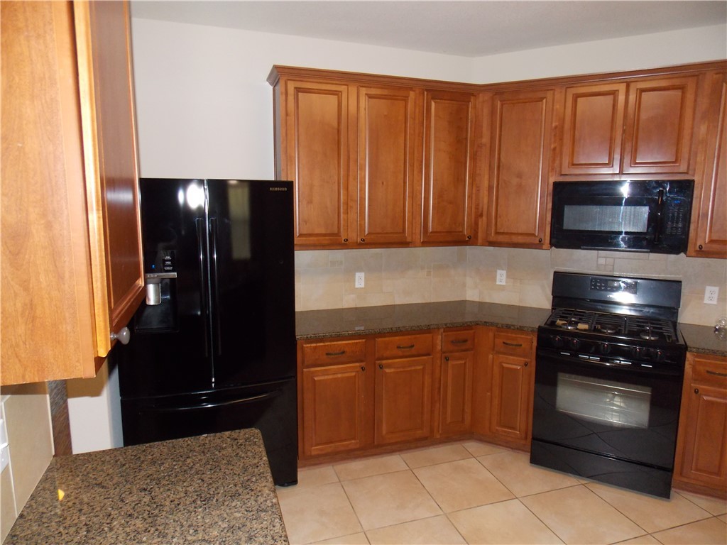 20961 Mandrake Drive Pflugerville, TX 78660 - Photo 17 of 34 a kitchen with granite countertop a refrigerator stove and microwave