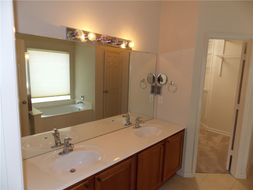 20961 Mandrake Drive Pflugerville, TX 78660 - Photo 22 of 34 a bathroom with a double vanity sink a mirror and a shower