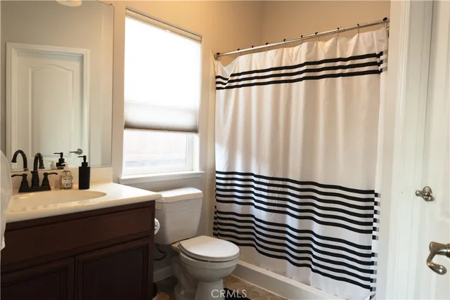 a bathroom with a sink a toilet a mirror and shower curtain