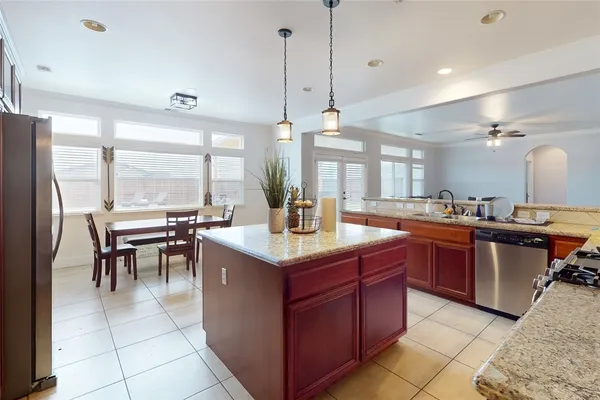 a kitchen with stainless steel appliances granite countertop a stove a refrigerator a sink and a dining table