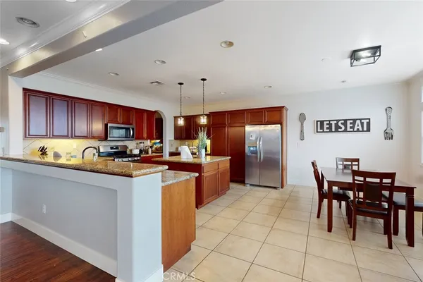 a kitchen with stainless steel appliances granite countertop a stove top oven a sink a dining table and chairs