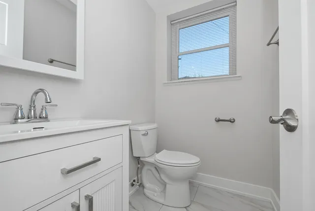 a bathroom with a toilet sink vanity and mirror