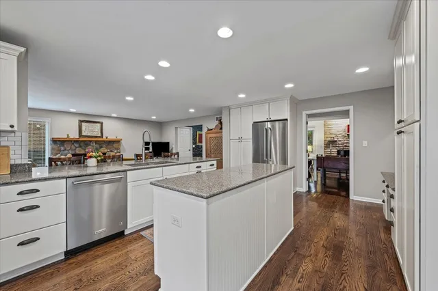 a kitchen with stainless steel appliances kitchen island granite countertop a refrigerator and a sink