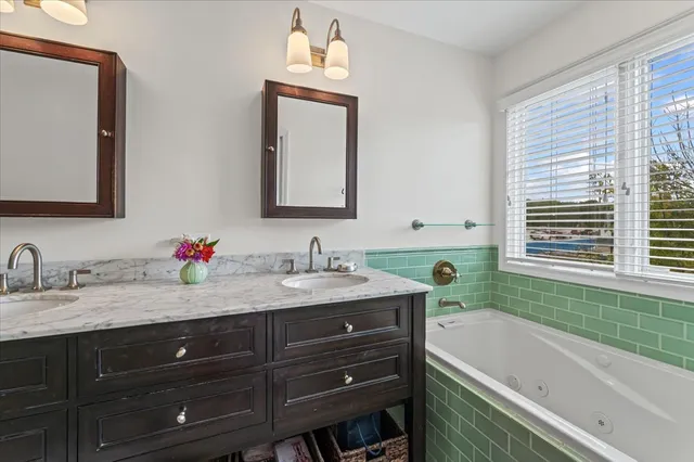a bathroom with a tub double vanity sink and mirror