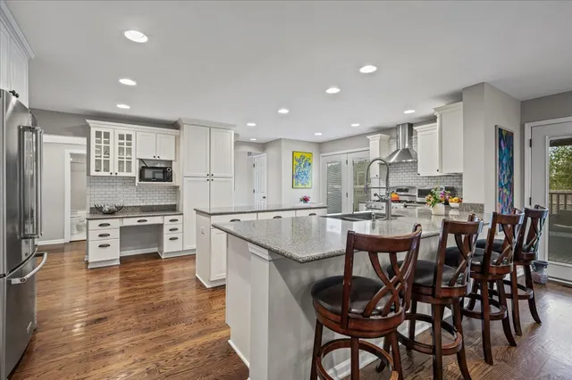 a kitchen with stainless steel appliances a stove a sink a kitchen island with chairs and refrigerator
