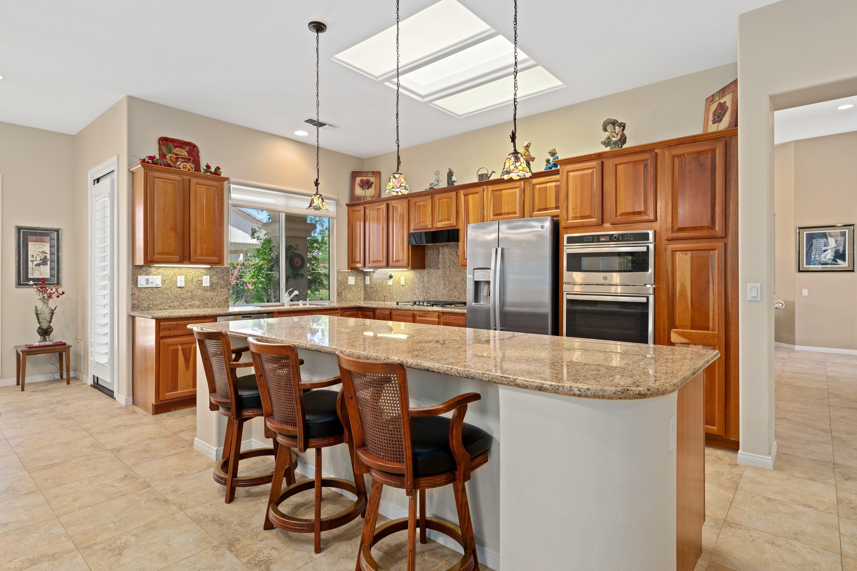 a kitchen with stainless steel appliances granite countertop a table chairs stove and refrigerator