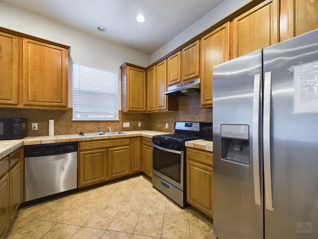 a kitchen with stainless steel appliances granite countertop a refrigerator a stove a sink and dishwasher