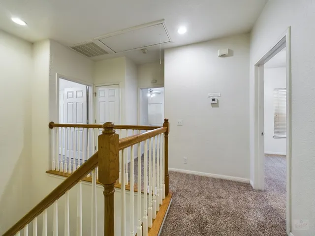 a view of a hallway with a hardwood floor and stairs