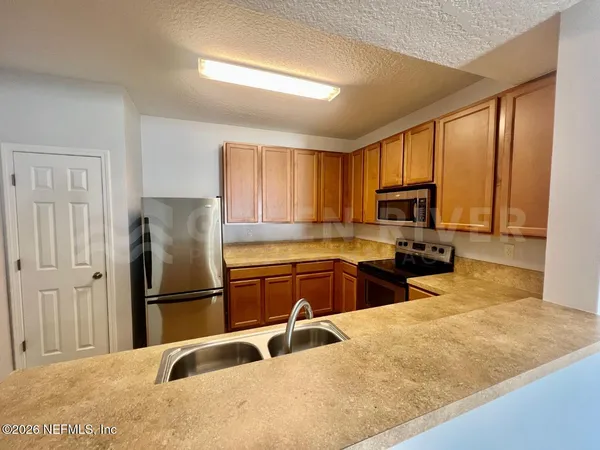 a kitchen with granite countertop a refrigerator sink and cabinets